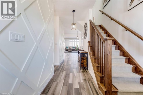 Interior hallway with white geometric wall paneling, wood-look tile flooring, and a staircase. - 18 Crossbridge Avenue, Kitchener