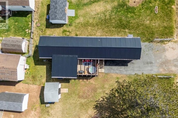 Aerial view of a mobile home with a black metal roof, showing a deck with a hot tub and surrounding yard. - 18 Daisy Lane, Riverview