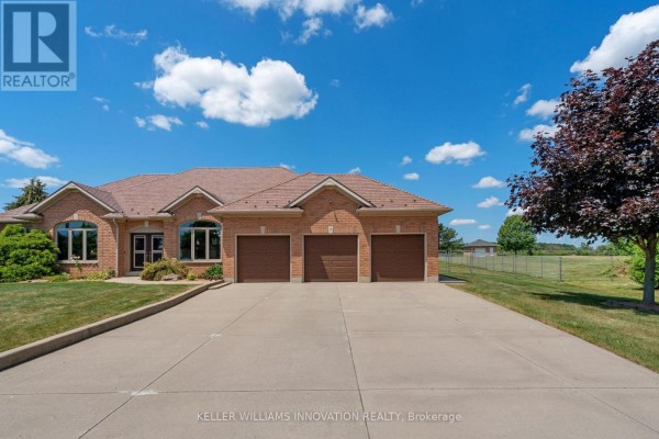 Front exterior of a brick house with a paved driveway leading to a triple garage. - 18 Featherstone Avenue, Haldimand