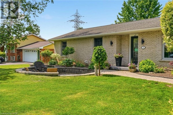 Side view of the brick house showing a circular seating area with chairs on a paved patio. - 18 Fireside Drive, Flamborough