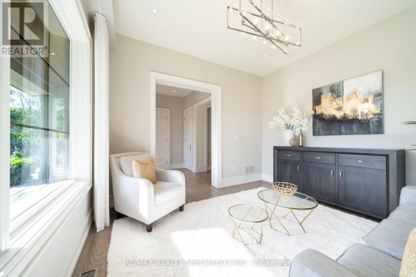 Living room with a large window, white rug, armchair, sofa, and a dark grey credenza. - 18 Florence Drive, Oakville