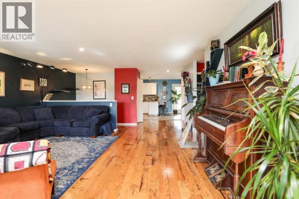 Basement living area with a sofa, armchair, projection screen, and colorful wall posters. - 18 Garden Place, Magrath