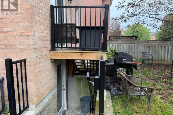 Backyard view of a raised deck with black railings, a lower door, and outdoor furniture. - 18 Harkins Drive, Ajax