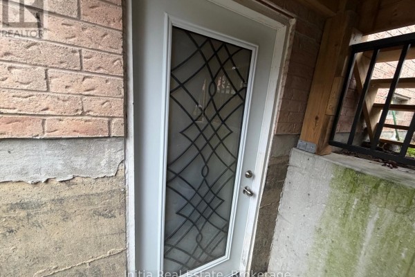 Close-up of a white exterior door with frosted glass featuring a diamond pattern and brick wall. - 18 Harkins Drive, Ajax