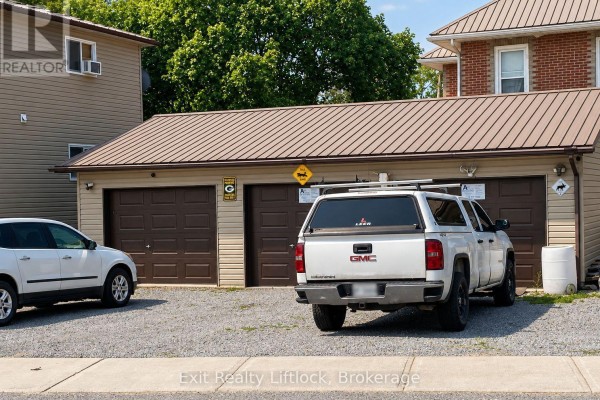 A three-bay garage with brown doors and metal roofing, parked cars, and white siding on the side. - 18 Helen Street, Asphodel Norwood