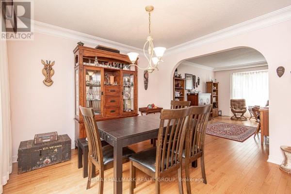 Dining room with a dark wood table and chairs, china cabinet, and an archway to a living area. - 18 Hesse Crescent, Ottawa