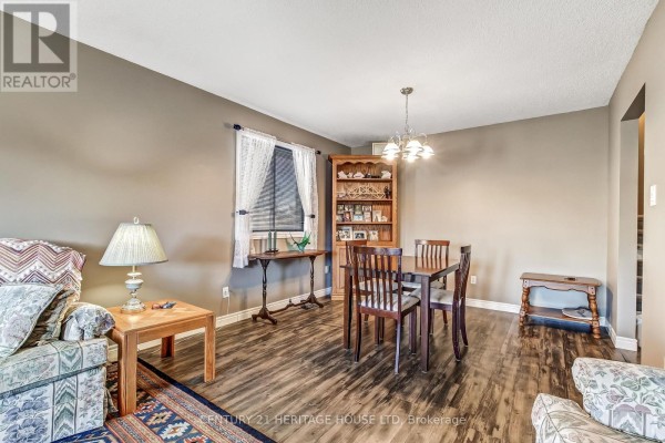 Dining area with a wooden table and chairs, a hutch, and laminate flooring. - 18 Hickory Boulevard W, Strathroy Caradoc