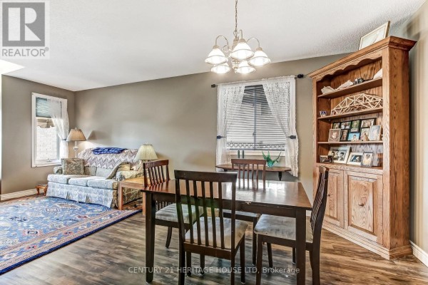 Dining room with a wooden hutch, table, and chairs near a window. - 18 Hickory Boulevard W, Strathroy Caradoc