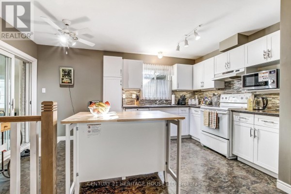 White kitchen with light wood island, stainless steel appliances, and tiled backsplash. - 18 Hickory Boulevard W, Strathroy Caradoc