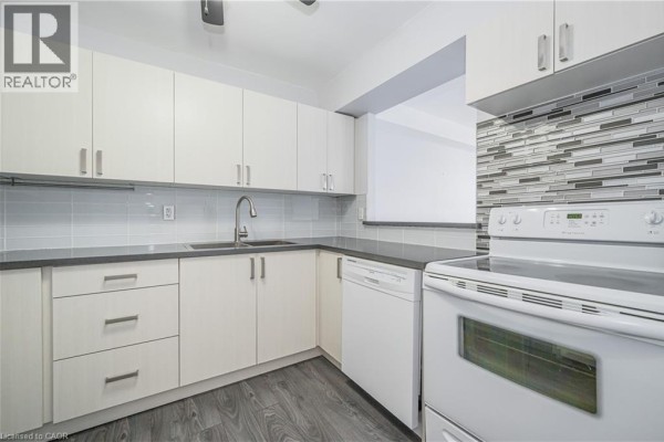 Modern kitchen with white cabinetry, grey countertops, and a white stove. - 18 Holborn Court Unit# 211, Kitchener