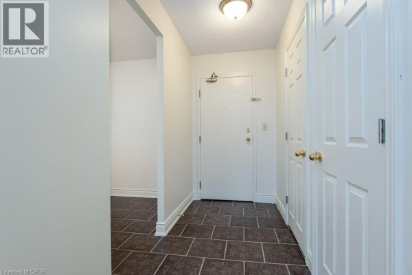 Apartment entryway with dark tile flooring, white walls, a white door, and two closets. - 18 Holborn Court Unit# 409, Kitchener