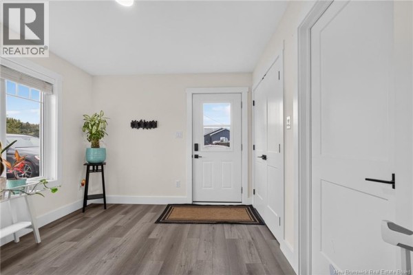 Interior entryway with grey wood-look flooring, white walls, and a white front door. - 18 Hope Road, Steeves Mountain