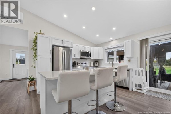 Modern kitchen with white cabinetry, a white island with bar stools, and stainless steel appliances. - 18 Hope Road, Steeves Mountain