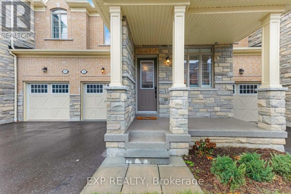 Close-up of the covered front porch of a townhouse with stone pillars and a brown door. - 18 Hough Lane, Ajax