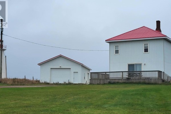 Side view of a white garage with a red roof, next to a white house with a red roof and deck. - 18 Light House Road, Monticello