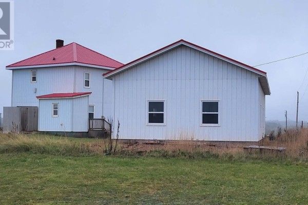 White metal clad garage with a red roof, two garage doors, and a view of the ocean under a blue sky. - 18 Light House Road, Monticello