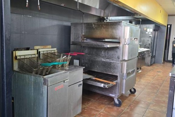 Commercial kitchen with deep fryers and a stacked pizza oven. - 18 Market Street Unit# B, Brantford