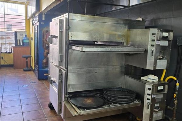 A commercial pizza oven with multiple racks and baking trays below. - 18 Market Street Unit# B, Brantford