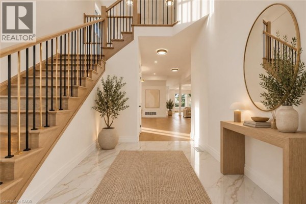 Spacious entryway with marble flooring, light wood staircase with black railings, and console table. - 18 Miles Road, Hamilton