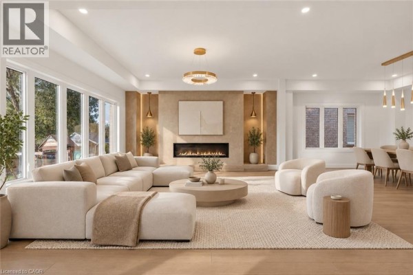 Open-concept living room with sectional sofa, round coffee table, fireplace, and large picture windows. - 18 Miles Road, Hamilton