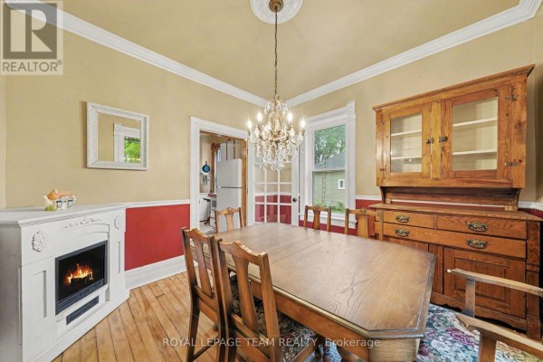 Dining room with a wooden table, chairs, fireplace, and a glass-front cabinet. - 18 Moffat Street, North Dundas