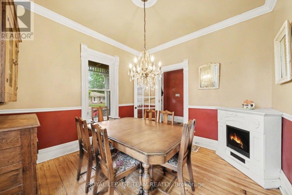Dining room with a wooden table, chairs, fireplace, and a chandelier. - 18 Moffat Street, North Dundas