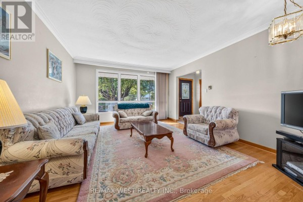 Living room with patterned sofas, floral rug, coffee table, and large window. - 18 Pheasant Valley Court, Markham