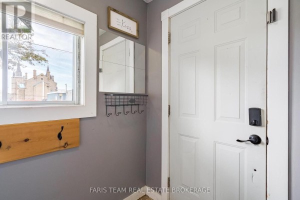 Interior view of a gray entryway with a white door, mirror, coat hooks, and a window. - 18 Poyntz Street, Penetanguishene