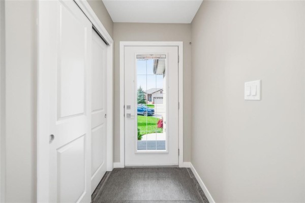 View from inside the entryway looking out the front glass door to the driveway. - 18 Prairieview Cove, Dugald