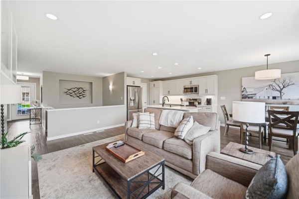 Open-concept living and dining area with a kitchen, sofas, and a dining table. - 18 Prairieview Cove, Dugald