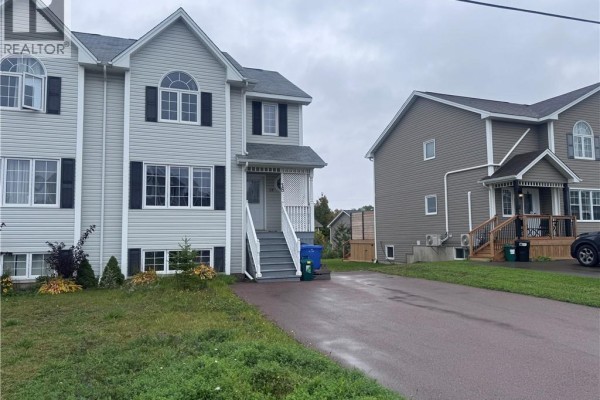 Side view of light gray townhouses with adjacent gray house and asphalt driveway. - 18 Rainford Court, Moncton