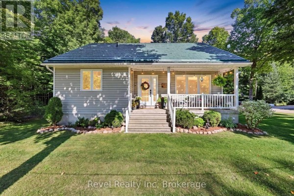 Front view of a beige bungalow with a covered porch, white railings, and steps leading to the front door. - 18 Rue Vanier Road, Tiny