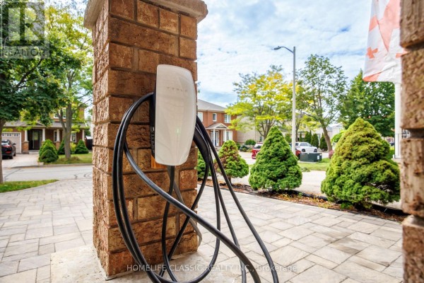 Close-up of an electric car charger mounted on a stone pillar near the garage. - 18 Rusty Trail, Vaughan