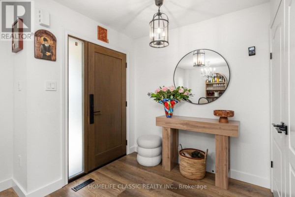 Interior entryway with a wooden double door, console table, round mirror, and decorative vase. - 18 Rusty Trail, Vaughan