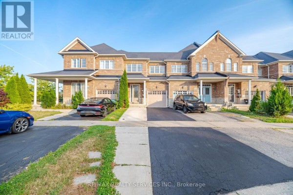 Exterior view of brick townhouses with garages and driveways on a sunny day. - 18 Seedland Crescent, Brampton