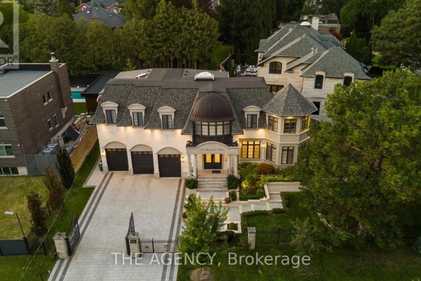 Gated entrance with stone driveway and landscaped front yard. - 18 Suncrest Drive, Toronto