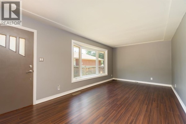 Living room with large bay window, gray walls, and dark hardwood flooring - 18 Tweedsmuir Avenue, Sarnia