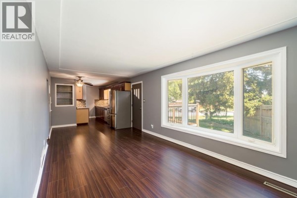 Open living area with bay window, gray walls, and access to kitchen - 18 Tweedsmuir Avenue, Sarnia