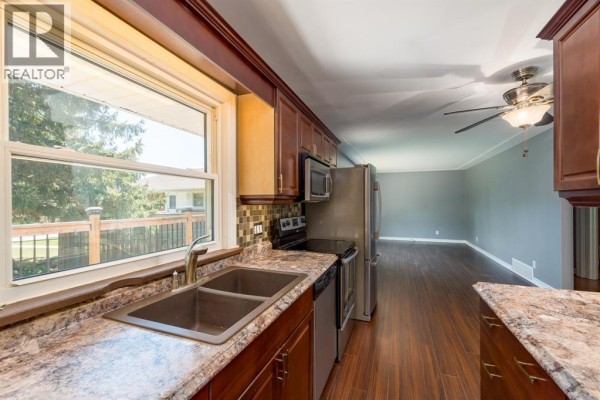Kitchen with dark wood cabinets, stainless steel appliances, and granite countertops - 18 Tweedsmuir Avenue, Sarnia