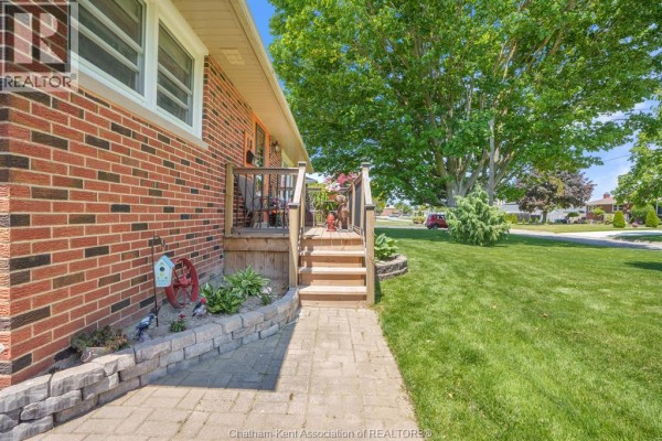 Rear side exterior of a brick house with a wooden deck, landscaping, and a fenced backyard. - 18 Woodland Avenue, Chatham