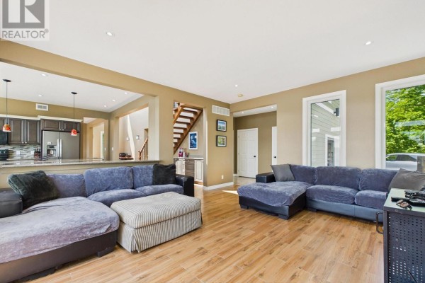 Spacious living room with a large sectional sofa, view of kitchen and stairs. - 180 Allison's Point Road, Huntsville