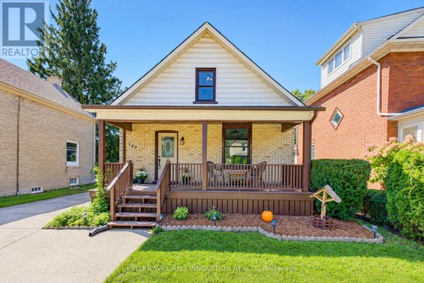 Front view of a yellow brick house with a covered porch, wooden railings, and a manicured lawn. - 180 Hewat Street, Cambridge