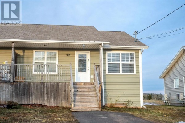 Close-up of the front entrance of a light green townhouse with white trim and a glass-paneled door. - 180 Norwood Road, Charlottetown