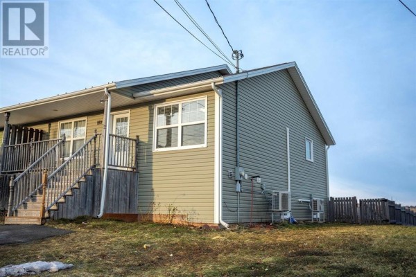 Right side exterior view of the townhouse, highlighting the siding, a window, and the roofline. - 180 Norwood Road, Charlottetown