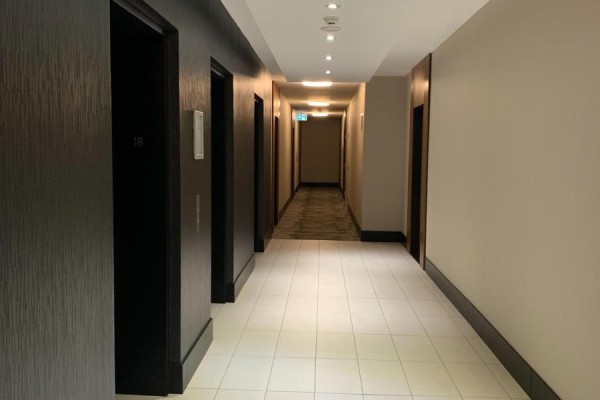 Apartment hallway with beige tile floor and wood front door. - 1801 - 1 Market Street, Toronto