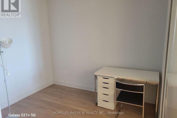 Empty small room with a white desk, a black chair, and a floor lamp. - 1801 - 2920 Hwy 7 Road, Vaughan