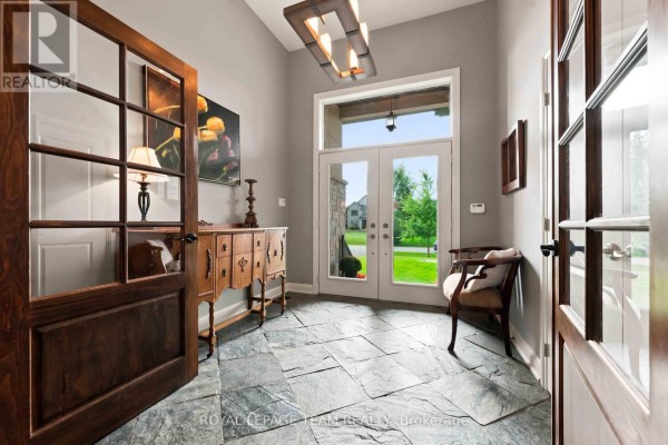 Foyer with stone tile floor, glass double doors, and antique wooden furniture. - 1801 Cedarlakes Way, Ottawa