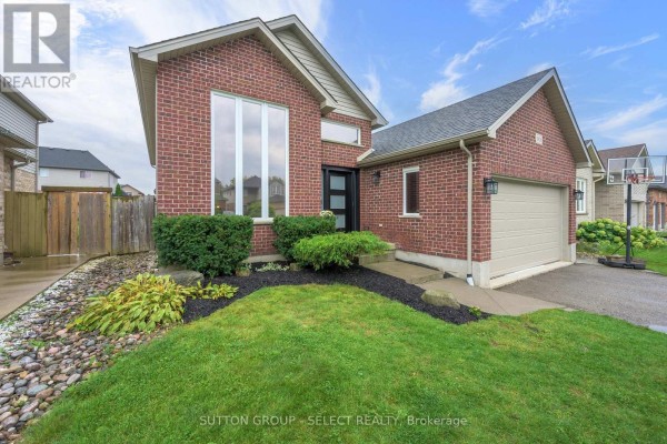 View of the red brick house exterior with a large front window and manicured landscaping. - 1801 Seymour Crescent, London North
