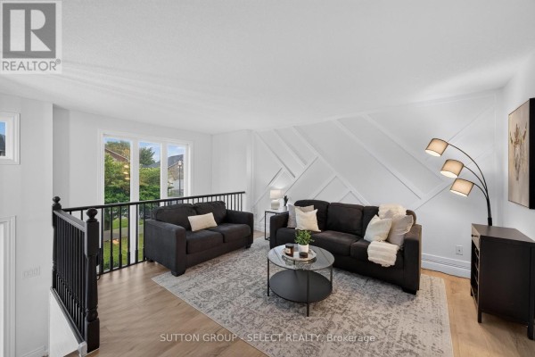Living room with two dark sofas, patterned rug, glass coffee table, and decorative wall paneling. - 1801 Seymour Crescent, London North