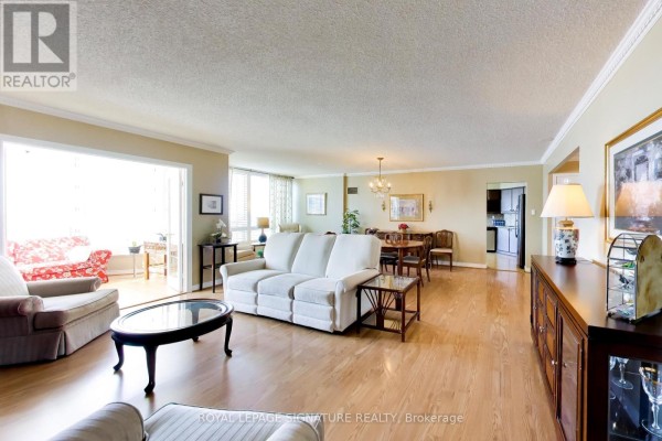 Open concept living and dining area with beige walls, light wood floors, and access to a sunroom. - 1802 - 1 Clark Avenue W, Vaughan